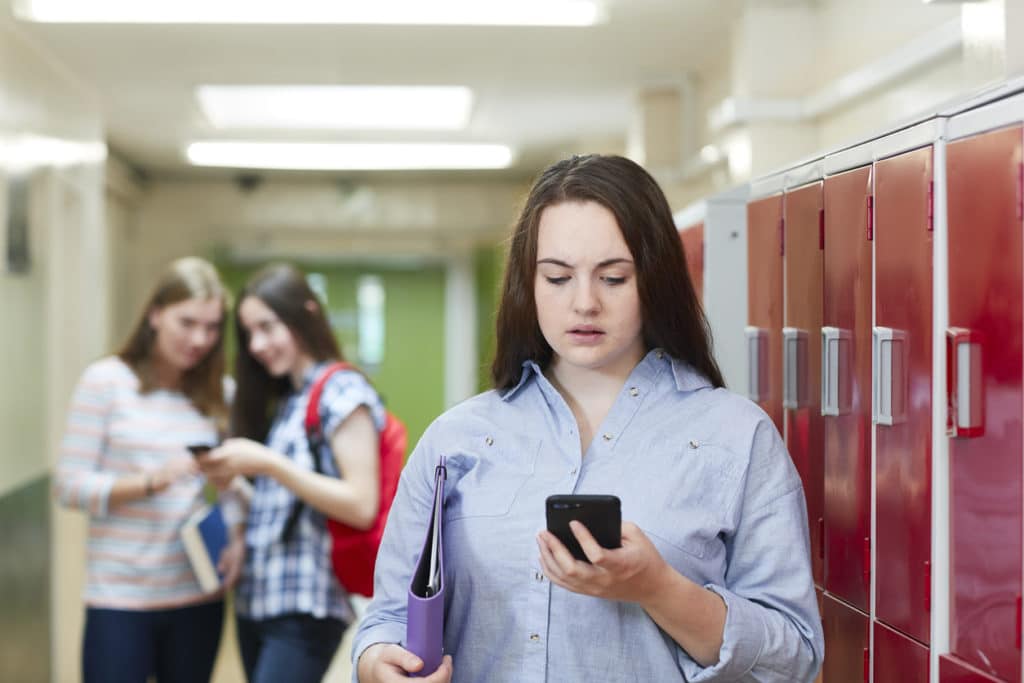 Female high school student bullied by text message in corridor